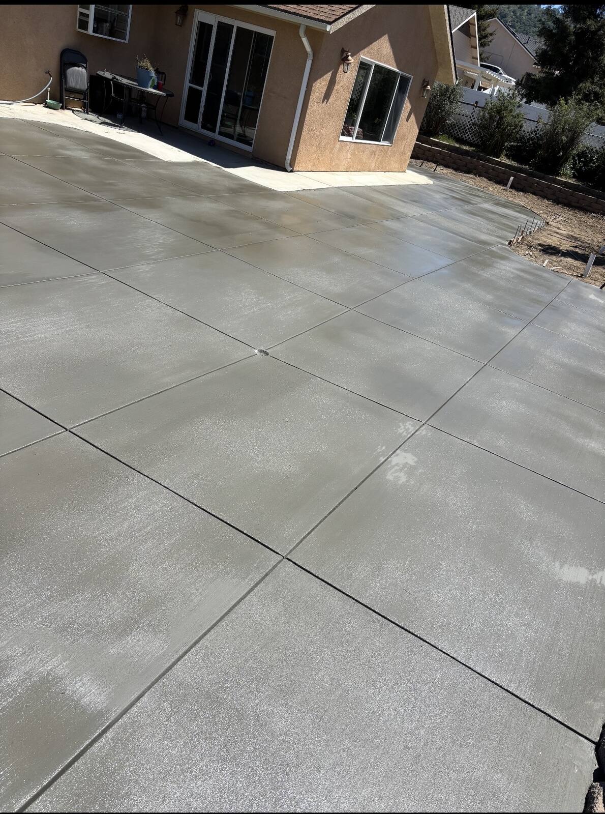 Large broom finished concrete slab beside a house, with control joints cut in a clean grid
