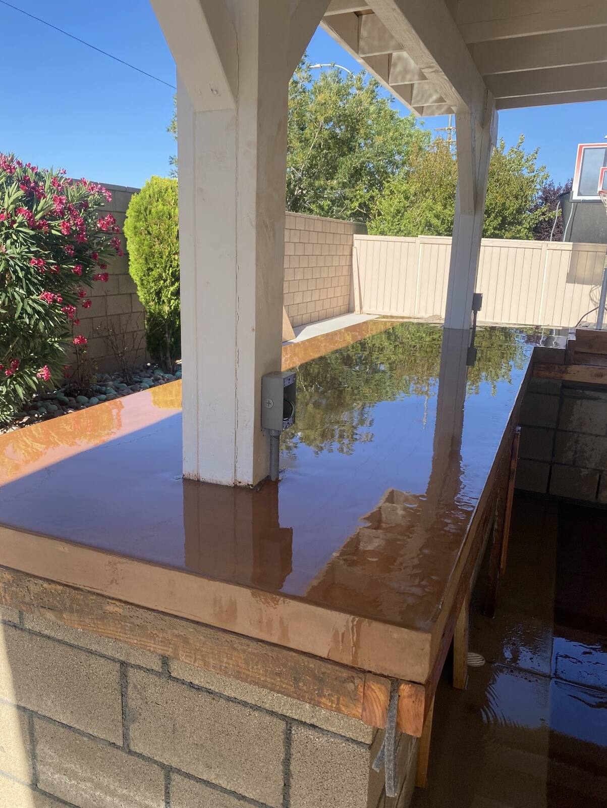 Outdoor bar with a high gloss poured concrete countertop on a block base, under a patio cover